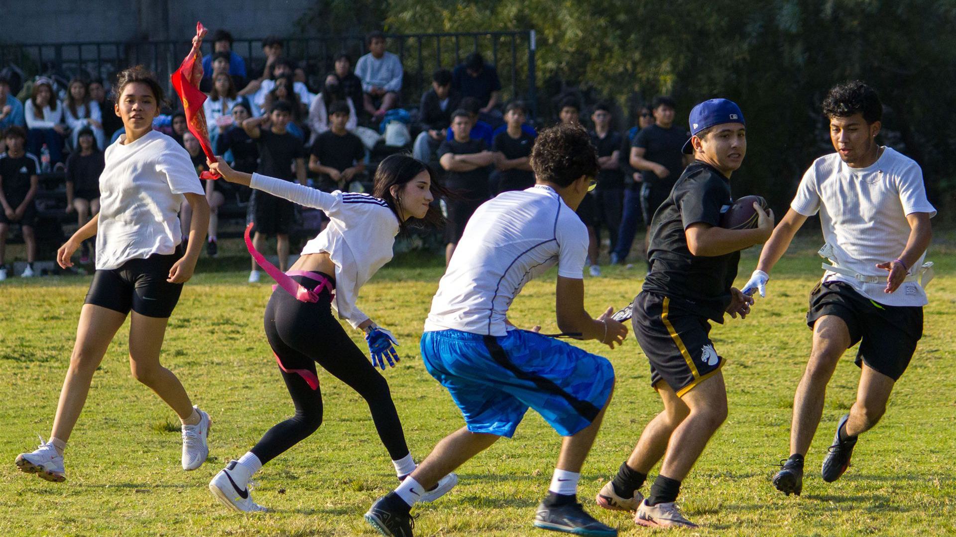 Eine Gruppe junger Erwachsener lieferte sich an einem sonnigen Tag ein spannendes Flag-Football-Spiel.