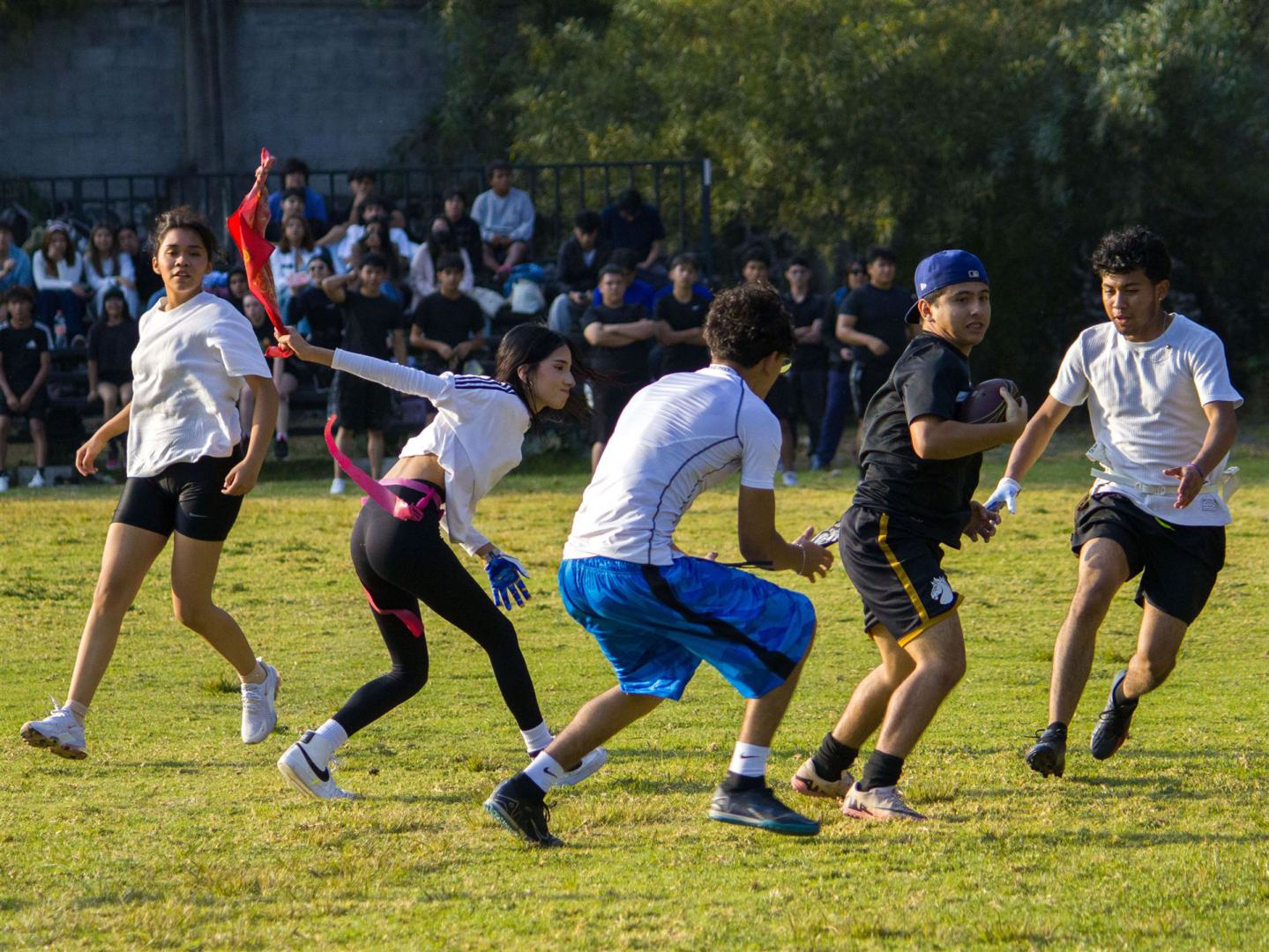 Eine Gruppe junger Erwachsener lieferte sich an einem sonnigen Tag ein spannendes Flag-Football-Spiel.